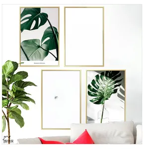 Detail of four Nordic wall art pieces featuring green Monstera leaves and gold frames