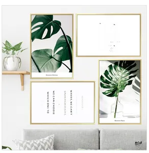 Close-up of Nordic monstera leaf prints and art typography in brushed gold frames