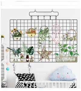 Detail of black metal wire wall grid with pink dreamcatcher and decorative home accessories