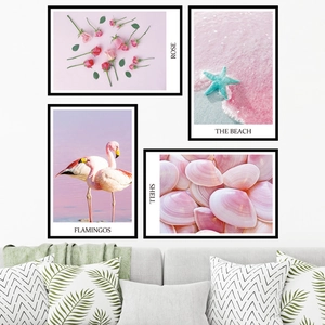 Pink flamingo and beach shells wall art set in black frames above a cozy Nordic sofa