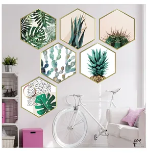 Detail of hexagonal golden frames featuring tropical green plants on a pink wall