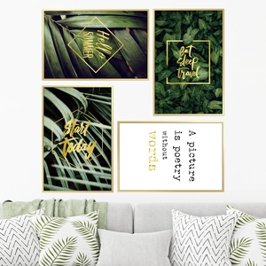 Lot de 4 tableaux muraux plantes tropicales avec cadres dorés au-dessus d'un canapé gris