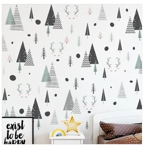 Détail de stickers muraux forêt nordique avec pins et élan dans une chambre d'enfant douce