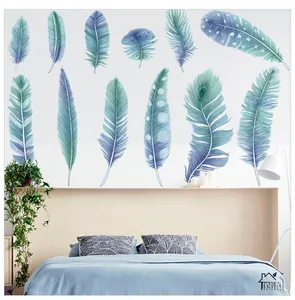 Close-up of blue watercolor feather wall stickers on a cozy bedroom headboard wall