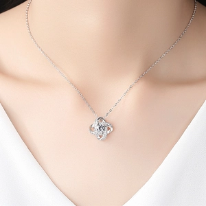 Elegant silver spinning clover necklace with a central crystal on a woman neck