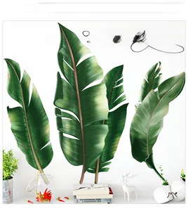 Détail des stickers muraux feuilles tropicales vertes dans un décor de salon minimaliste