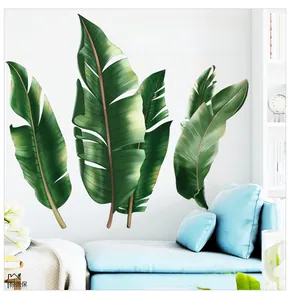 Détail de stickers muraux feuilles de bananier tropicaux sur mur blanc et canapé bleu