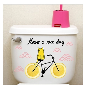 Waterproof toilet sticker showing a yellow cat on a lemon-wheel bicycle with pink clouds