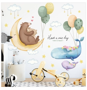 Detailed view of cartoon whale and moon wall stickers in a cozy nursery room setting