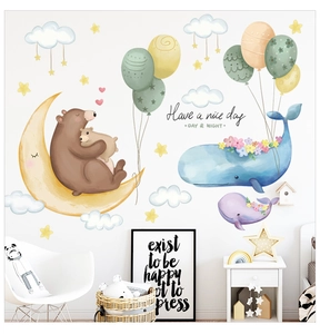 Detail view of cartoon bear on moon and whale wall stickers in a cozy nursery room