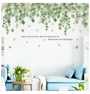 Detail of green leaf wall sticker with inspirational quote above a blue sofa