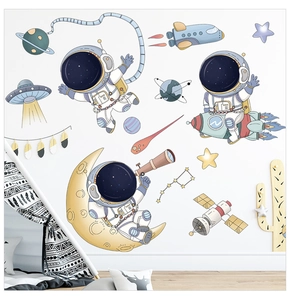 Detail of cartoon astronaut wall decals with planets and UFOs in a cozy kids room