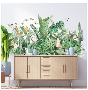 Detail of tropical plant wall decals with cats and monstera leaves in a cozy living room