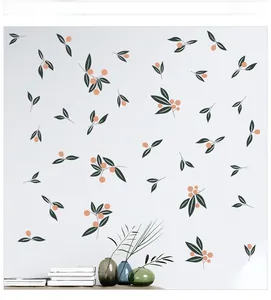 Detailed view of hand-painted green leaf and orange berry wall decals on a white wall