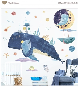 Detailed view of whale and planet wall decals on white wall above a baby crib in a nursery
