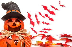 Close-up of Halloween pumpkin with witch hat, maple leaves and paper bat stickers