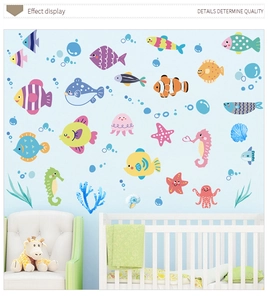 Detail view of cartoon ocean fish wall decals in a cozy nursery room setting