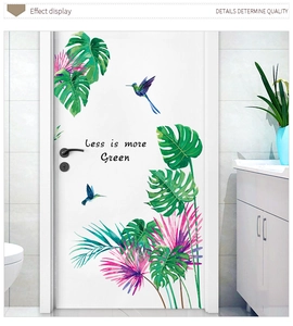 Macro detail of tropical monstera leaves and hummingbirds wall decals on a white door