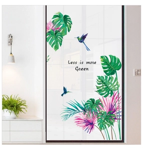 Detail of tropical monstera leaves and hummingbird wall decals on a glass door