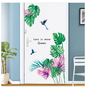 Detail of tropical monstera leaves and hummingbird wall decals on a modern white door