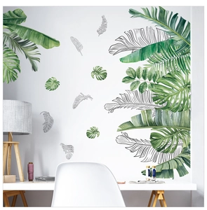Vue détaillée des stickers muraux feuilles de monstera et palmier sur un mur blanc moderne