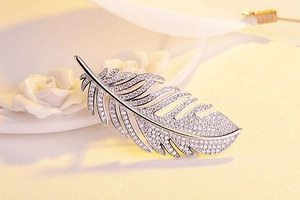 Detailed view of silver feather brooch with sparkling zircons on elegant white decor