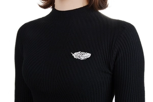 Silver feather brooch with zircon details pinned on a black turtleneck sweater