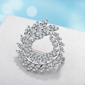 Détail d'une broche couronne en argent avec cristaux marquise sur support blanc