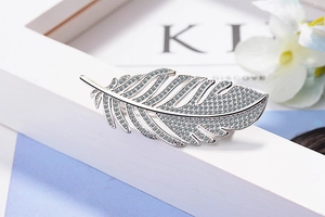 Close-up of feather brooch with inlaid zircons on a decorative white frame base