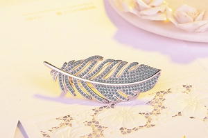 Detailed view of an elegant silver feather brooch inlaid with sparkling zircons