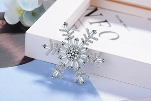 Vue macro latérale d'une broche flocon d'argent avec zircons étincelants sur textile bleu