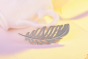 Detailed close-up of a silver feather brooch with shimmering zircon micro-pave setting