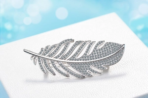 Macro shot of silver feather brooch with pavé set cubic zirconia on a white jewelry box
