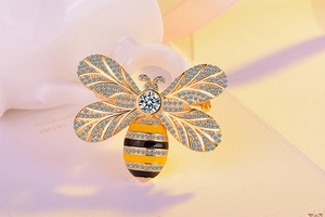Detailed macro view of a gold bee brooch featuring micro-pave cubic zirconia and enamel