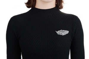 Detailed view of an elegant silver feather brooch pinned to a black knit cardigan