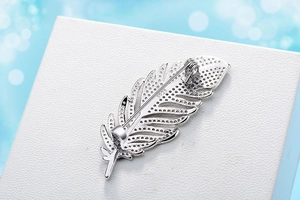 Close-up of feather-shaped S925 silver brooch with sparkling white cubic zirconia