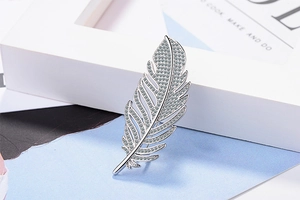 Detailed macro view of an elegant silver feather brooch with sparkling cubic zirconia