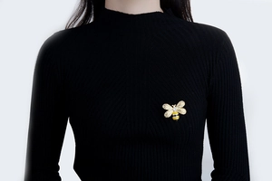 Detail of bee brooch with yellow enamel and clear zircon pinned on black knitwear
