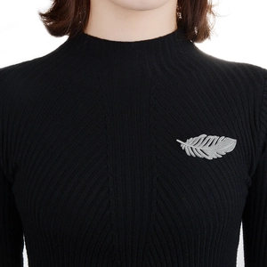 Elegant silver feather brooch with textured finish pinned on a black sweater for women