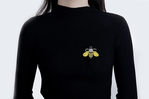 Detail of colorful bee brooch with crystals pinned on a black turtleneck sweater