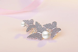 Detail of rose gold butterfly brooch with pavé crystals and elegant white pearls