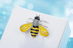 Detailed view of enamel bee brooch featuring sparkling white zircons and silver plating