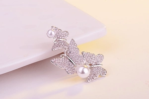 Detailed view of silver butterfly brooch featuring shimmering crystals and white pearls