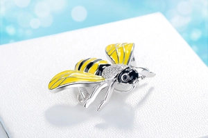 Detailed close-up of a luxury crystal bee brooch with yellow enamel on a jewelry box