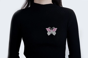 Close-up of butterfly brooch with rose red and white crystals on black sweater