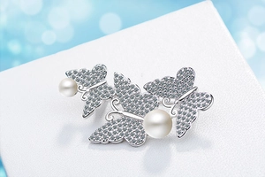 Detail of elegant butterfly brooch with shimmering crystals and white round pearls