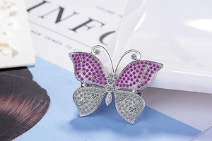 Detailed macro view of butterfly brooch with purple and white cubic zirconia on a plate