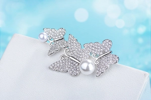 Macro shot of butterfly brooch with sparkling zircon inlay and two white pearls