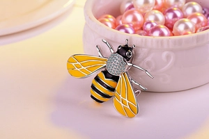Macro detail of bee brooch featuring yellow enamel wings and sparkling white crystals