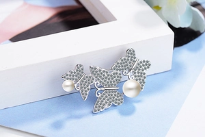 Detailed view of silver butterfly brooch with sparkling rhinestones and white pearls
